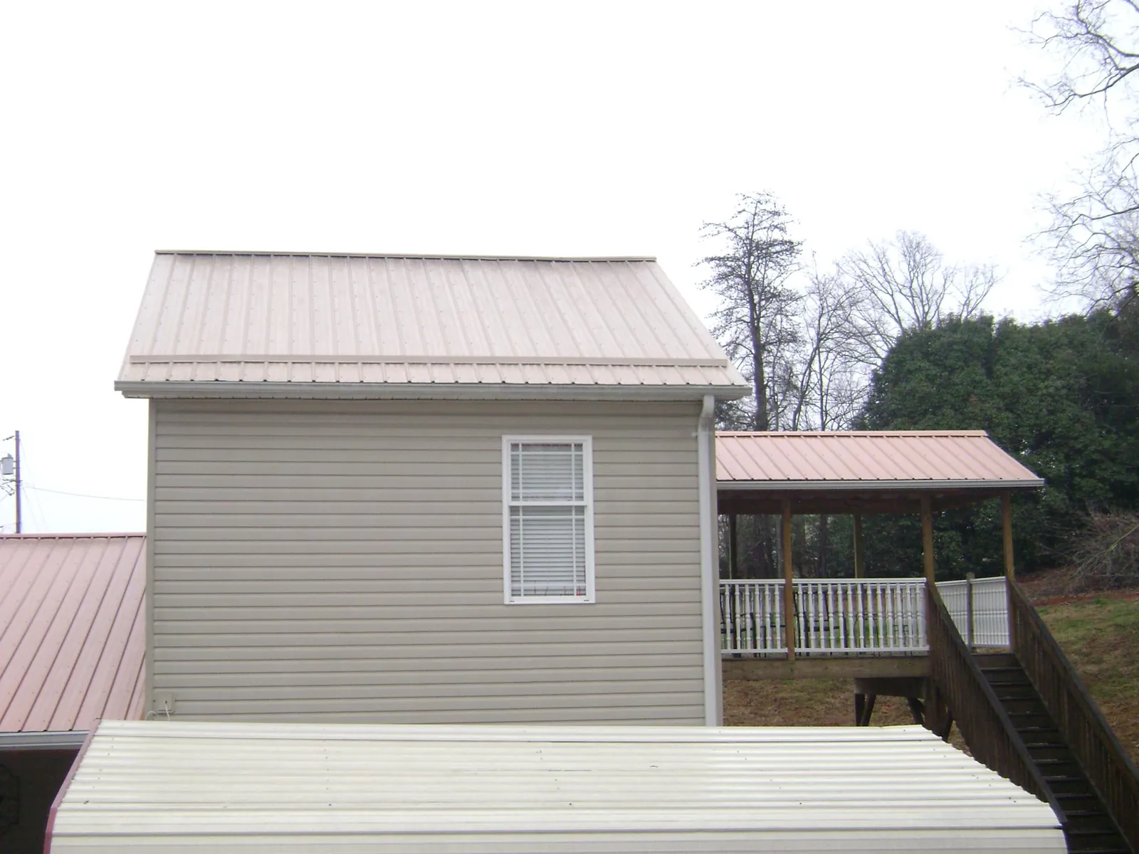 Tan metal roofs on a two story addition and attached porch, from a Roof Replacement job in Winchester